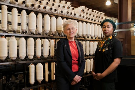 Two women stand in front of shelves containing reams of cotton