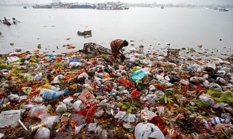 A woman collects items thrown into the Ganges as religious offerings