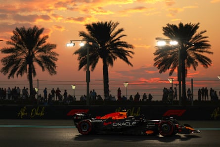 Yuki Tsunoda driving his Red Bull at sunset in Abu Dhabi against a backdrop of palm trees