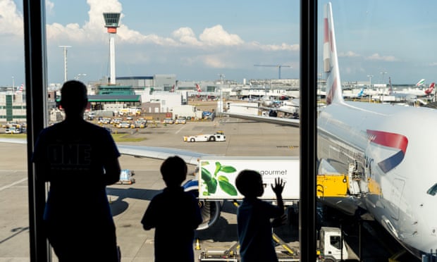 Young family and child by windows waiting to board plane at London Heathrow airport