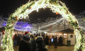 A Christmas market in Warsaw, Poland. People stand under a brightly-lit arch.