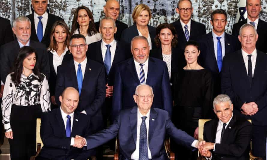 Israel’s president, Reuven Rivlin, sits next to Prime Minister Naftali Bennett and the foreign minister, Yair Lapid, as they pose for a group photo with ministers of the new Israeli government