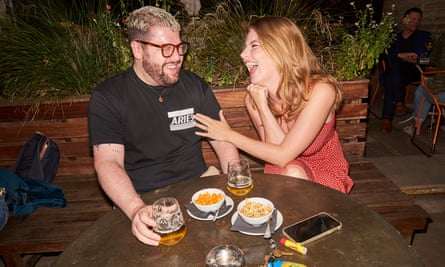 Caroline and Ryan sitting outside at a table having drinks and laughing