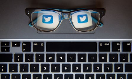 The Twitter logo reflected in a pair of glasses above a keyboard