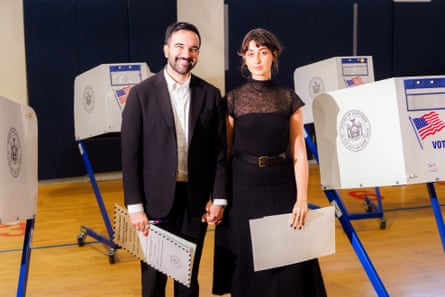 a husband and wife stand for a photo while holding documents