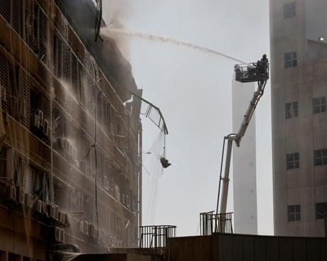A firefighter on crane douses a smoking building with water