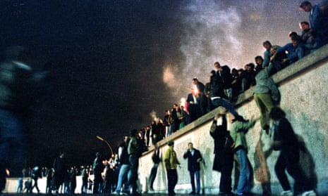 East Germans climb the Berlin Wall at the Brandenburg gate on 10 November 1989.