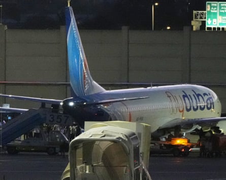 A flydubai plane at an airport gate at night