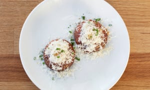 Two round 'cakes' covered in grated cheese on a round white plate