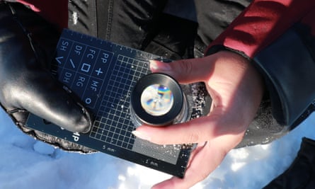 hand looking at a snow crystal through a lens