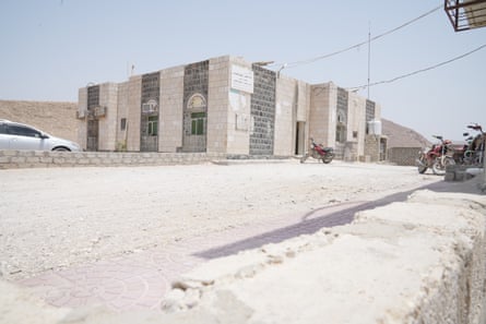 A single-storey building in a desert with a sign in Arabic on it