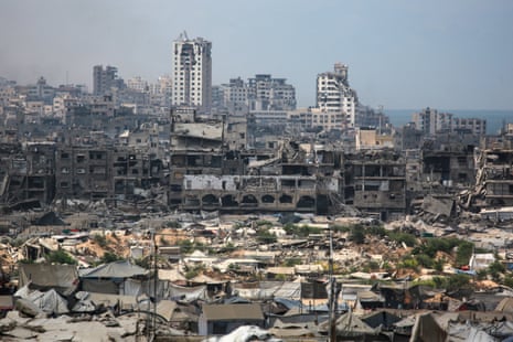 Buildings destroyed in Israeli airstrikes surround makeshift shelters for displaced Palestinian people in Gaza City.