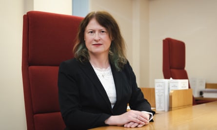 Victoria McCloud, a woman with brown hair in a dark suit and white blouse, sitting at a desk