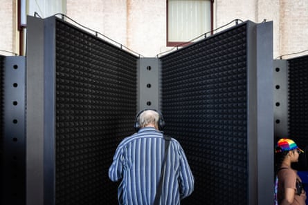 Man standing in recording booth with headphones on, viewed from behind