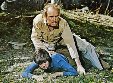 Duvall crouching over a child in a protective pose
