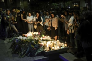 Members of the public placing lit candles and flowers.