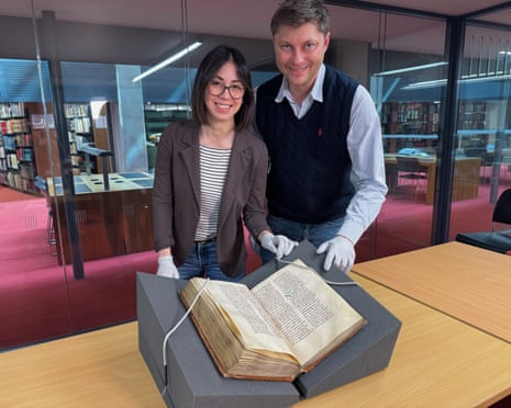 Elisabetta Magnanti and Mark Faulkner wearing protective gloves with Trinity College Dublin's copy of Bede's Ecclesiastical History.of the English People