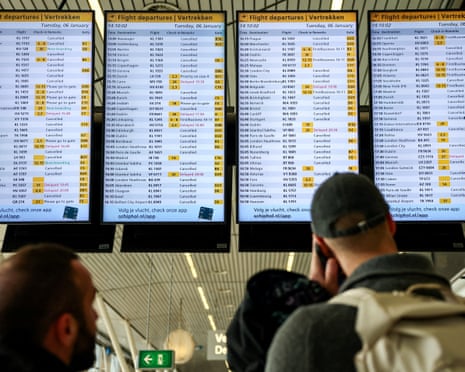 People look at departures screens showing delayed and cancelled flights at Amsterdam Airport.