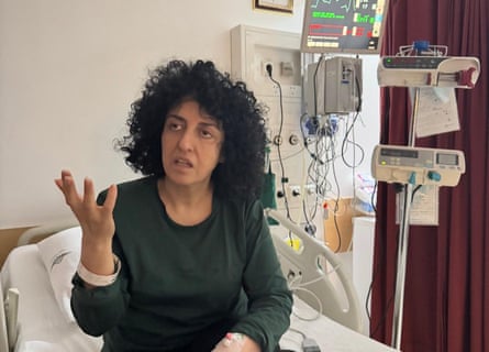 A middle-aged woman in a hospital bed connected to a monitor