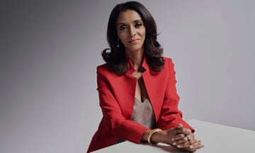 Zeinab Badawi wearing a red jacket sitting at a table with a grey background