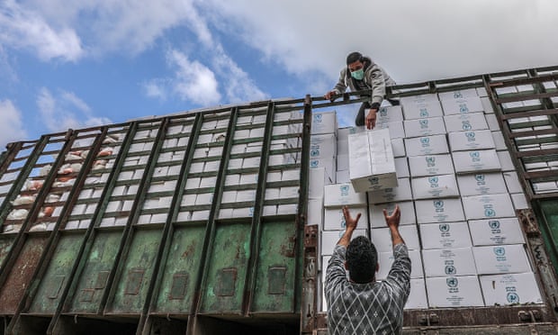 Workers for the United Nations Relief and Works Agency (UNRWA) unload food supplies for refugee families in Gaza City.