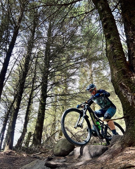 A mountain biker navigating over a rocky path in a forest.