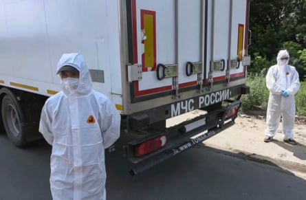 Men in white protective safety gear stand next to a truck