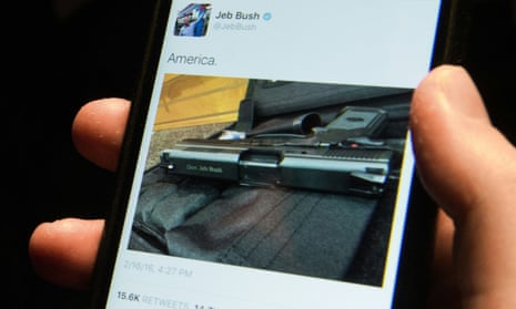 A man looks at a tweet from Jeb Bush showing a gun and captioned ‘America'