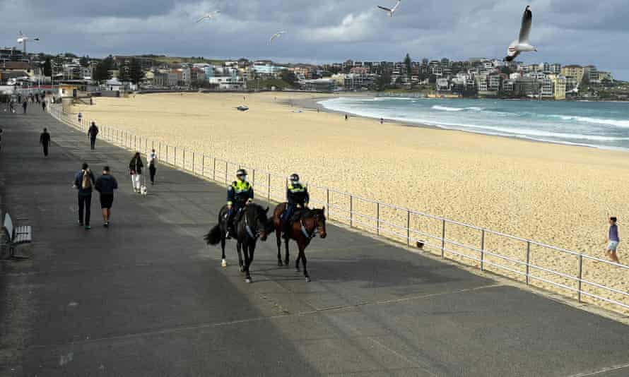 Mounted police patrol Bondi Beach in Sydney, Australia on 28 June. With the entire state of NSW under Covid lockdown restrictions, check our full guide to the new and updated coronavirus rules around wearing face masks, home visitors, the 5km radius travel limit, curfew and exercise time limits.