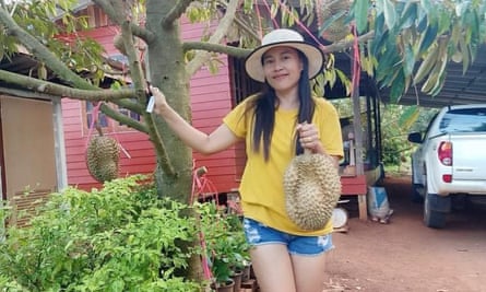Yanipak Arunsinprasreat holds some durian fruit next to a durian tree