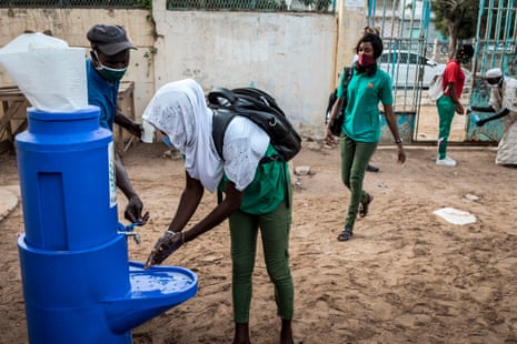 A High School student at the Lycee Blaise Diagne washes her hands as she arrives for her first day back at school in Dakar on 25 June, 2020.