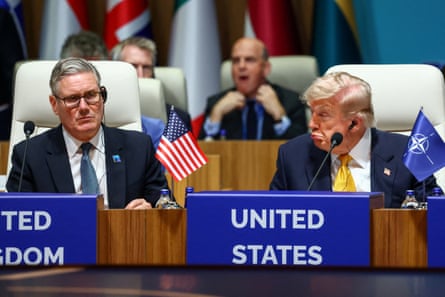 Keir Starmer sits next to Donald Trump. They are at an official event with signs in front of them reading ‘United Kingdom’ and ‘United States’.