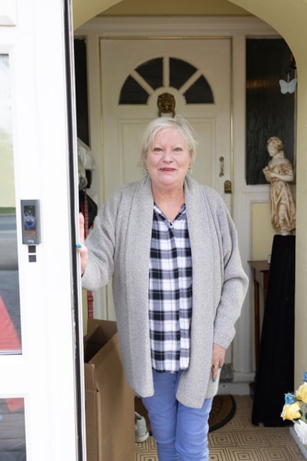 Lyn Loines standing with one hand resting on her front door, posing for a photograph