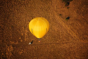 A balloon flies over a field, which has turned brown and dried out in the prolonged spell of dry weather, during the Bristol International Balloon Fiesta