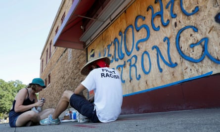 La gente se sienta junto a un mural en Kenosha, Wisconsin, el viernes.