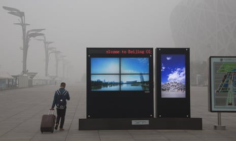 Screens show Beijing’s Olympic Green park under blue skies amid heavy smog. 