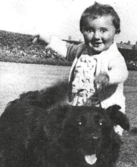A b/w photo of a toddler with a beaming face next to a happy-looking black dog