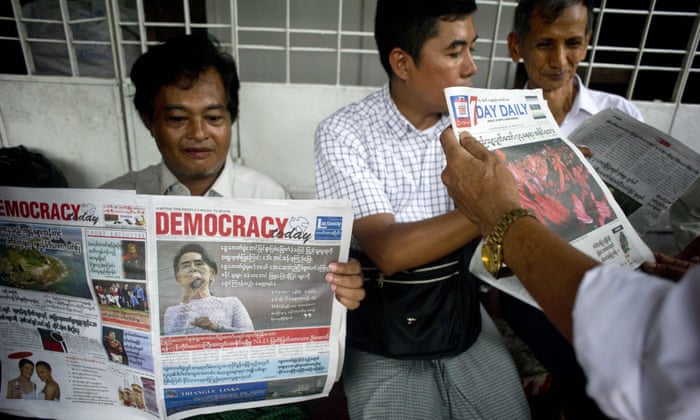 Supporters of Myanmar opposition leader Aung San Suu Kyi read the official results of the elections from a newspaper outside the National League of Democracy headquarters in Yangon