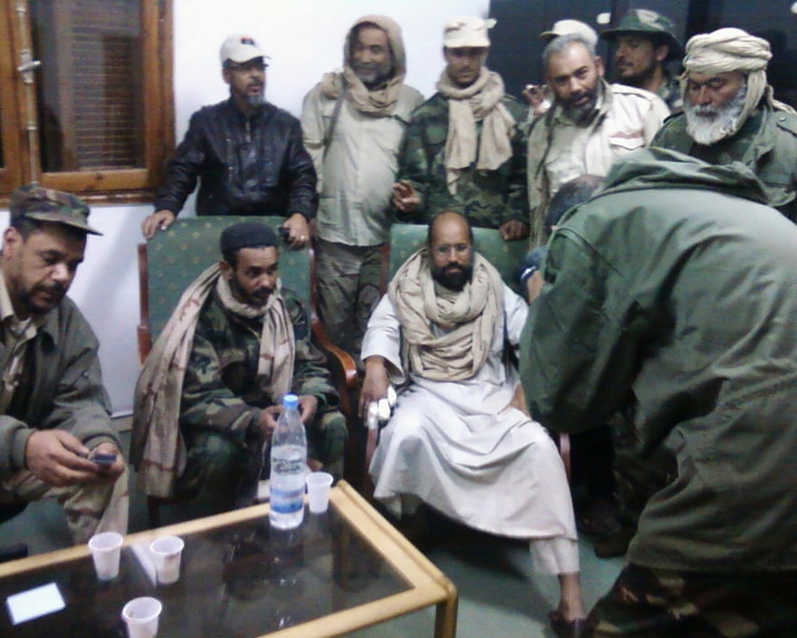 Saif al-Islam Gaddafi sitting with his captors in Obari airport in November 2011.