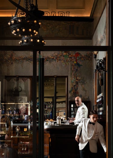 A barman and a waiter dressed in white tuxedos in a bar in Milan