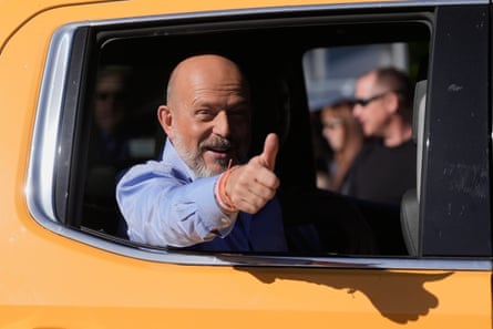 A man giving a thumbs-up sign from a car.