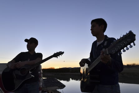 Two Mexican boys play guitars along the bank of Rio Bravo in Ojinaga