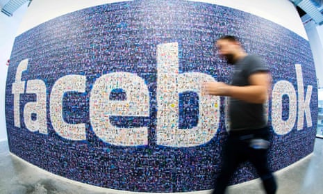 A man passes a Facebook logo