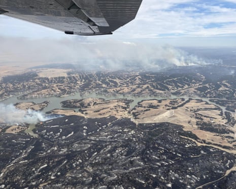 overhead view from aircraft of burned areas and smoke rising