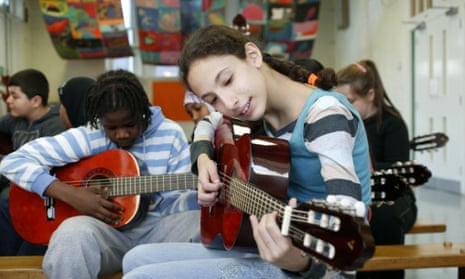 Pupils learn to play the guitar in a music lesson.