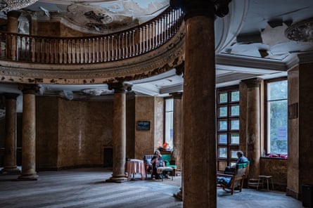 Homeless people sit in the decaying, pillared entrance of an abandoned Soviet-era sanatorium