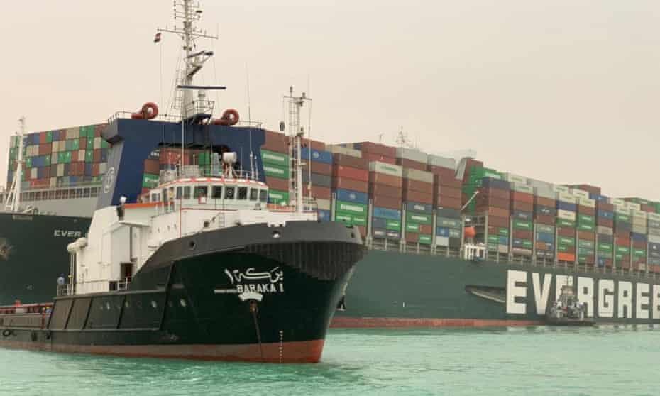 The stranded Ever Given container ship with an Egyptian tug boat in the Suez canal, Egypt, March 2021
