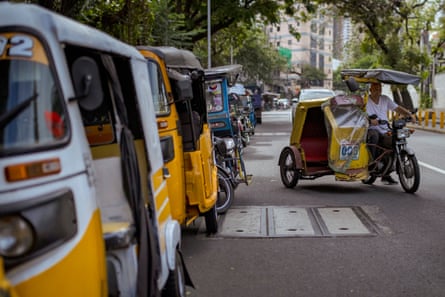 A tricycle driver drives off after receiving cash aid, amid rising fuel prices caused by the US-Israel war on Iran.
