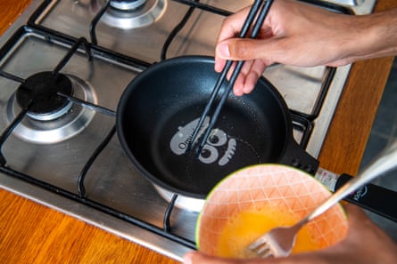 A bowl of beaten eggs sits next to a pan on a hob