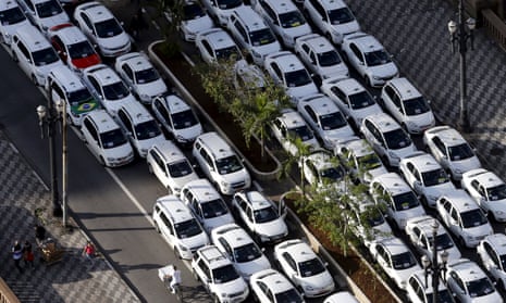 People pass taxis parked on the street during a protest against Uber in downtown São Paulo